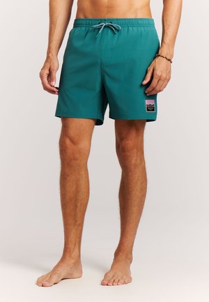 Türkisfarbene Badeshorts mit elastischem Bund, verstellbarem Kordelzug und einer seitlichen aufgesetzten Tasche mit farbenfrohem Logo. Schnell trocknender Stoff.