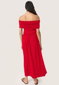Raudonas off-the-shoulder maksi suknelė su susiraukšlėjusiu audiniu, prigludusia liemene ir laisvai krentančiu sijonu. Turi elastingą liemens juostą ir kasdienius batus.