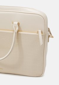 Beige bærepose til laptop med krokodillestruktur, glat finish, dobbelt håndtag og en guldfarvet lynlås, der har en frontlomme.