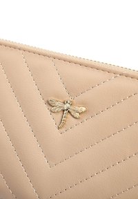 Beżowy skórzany portfel z pikowanym wzorem w zygzak, złotym akcentem w postaci ważki oraz kontrastowym przeszyciem, z zamknięciem na zamek.