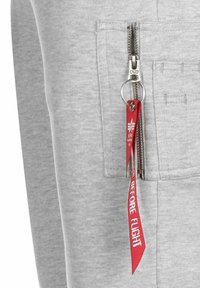 Gray sweatshirt with a zippered pocket. Features a silver zipper, ring pull, and red fabric tag with "BEFORE FLIGHT" text. Soft texture.
