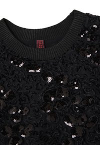 Maglione nero con una superficie testurizzata decorata con paillettes nere e argento. Collo a coste, senza altre decorazioni o elementi metallici visibili.