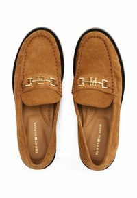 Suede loafers in tan with a rounded toe and a decorative gold chain accent. Black sole with perforated insole detailing.
