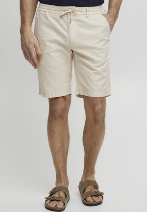 Beige katoenen shorts met een elastische tailleband en trekkoord, voorzien van zijzakken, boven de knie lengte en een relaxte fit.