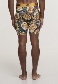 Calsoncillos bóxer para hombre con un patrón floral de rosas y detalles dorados. Presentan una tela suave, cintura elástica y un diseño ajustado.