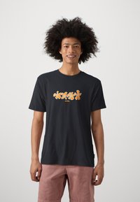 Black cotton t-shirt featuring a floral design in orange on the front. Short sleeves and a round neckline. Paired with light pink shorts.