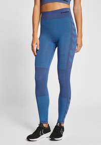 Blå atletiska leggings med mönstrad design, med varierande nyanser av blått och chevron-accenter på sidan. Elastisk midja.