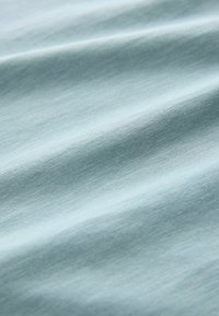 Svijetloplavi materijal s nježnim naborima i glatkom, finom pletenom teksturom.