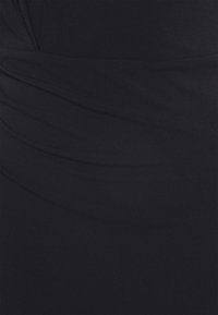 Tissu noir avec de subtils plis diagonaux créant texture et profondeur.