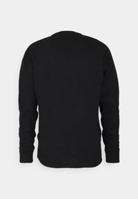 Pull en maille noire avec manches longues, encolure ronde, poignets et ourlet côtelés. Texture lisse et coupe ajustée sans motifs visibles.