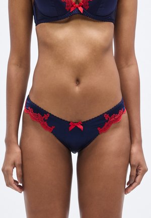 Granatowa bielizna z czerwonymi koronkowymi zdobieniami po bokach i małą czerwoną kokardką z przodu. Gładka faktura i dopasowany krój.