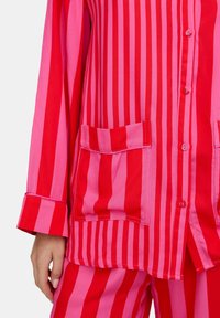 Rotes und rosafarben gestreiftes Lounge-Set mit einem Hemd zum Knöpfen, einem Kragen, zwei Brusttaschen und langen Ärmeln. Weicher Baumwollstoff.