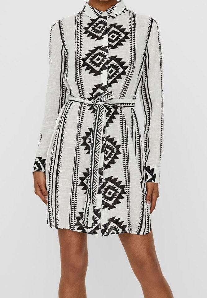 Långärmad skjortklänning i lätt, strukturerad tyg. Har ett djärvt svart geometriskt mönster på en vit bakgrund. Justerbart bälte.