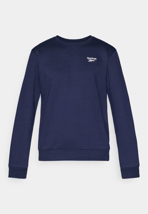 Mørkeblå genser med lange ermer, ribbestrikkede mansjetter og kant. Har en liten hvit Reebok-logo på brystet. Laget av et mykt stoff.