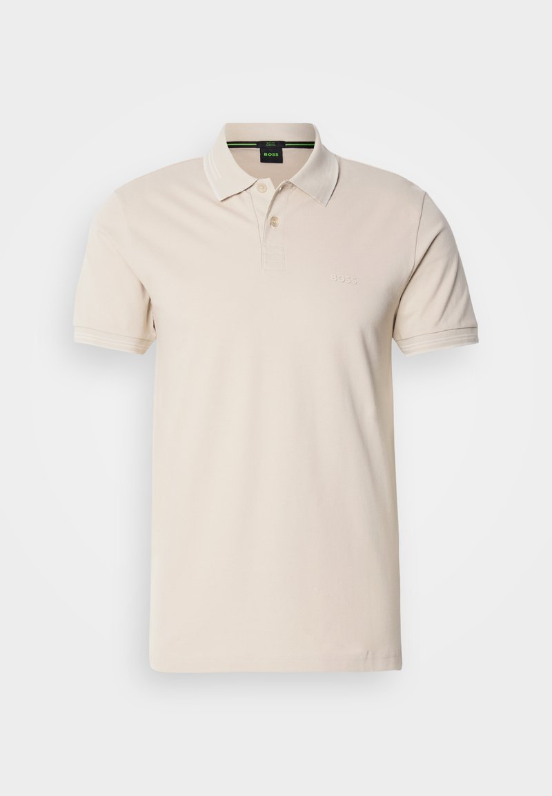 Polo shirt couleur crème en coton. Il présente un col classique, une patte de boutonnage à trois boutons, des manches courtes et un logo brodé sur la poitrine.