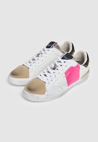 Zapatillas blancas y beige con un acento rosa, material texturizado de estampado de serpiente, forma redonda y suela de goma con desgaste visible.