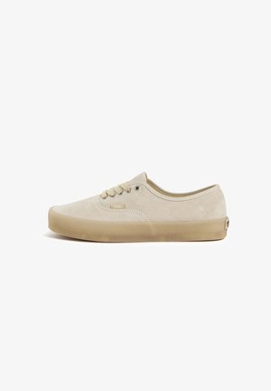 Basket basse beige Vans avec dessus en daim, semelle en gomme naturelle, lacets à l'avant et petit logo latéral et au talon.