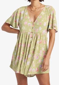 Grön blomklänning med V-ringning, korta fladdriga ärmar och knäppning framtill. Har rosa och blå blomsterblad på ett texturerat tyg.