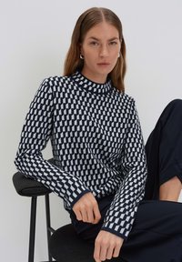 Navy und weiße kariert gestrickte Sweatshirt mit langen Ärmeln und einem hohen Kragen, das ein strukturiertes Muster und kontrastierende Bündchen aufweist.