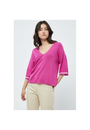 Lys pink V-hals strikket top med korte ærmer og hvid kant ved ærmerne. Stoffet er blødt med en afslappet, løs pasform.