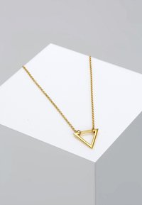 Collana d'oro con pendente triangolare, caratterizzata da un design elegante e una catena delicata, su uno sfondo di esposizione minimalista.