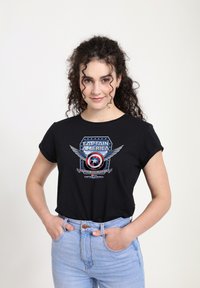 Černé tričko s krátkým rukávem s grafikou štítu Kapitána Ameriky s křídly a textem, vyrobené z měkké bavlny s volným střihem.