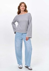 Grey long-sleeve sweater with a rounded neckline and white accents, paired with light blue wide-leg jeans and black-striped white sneakers.