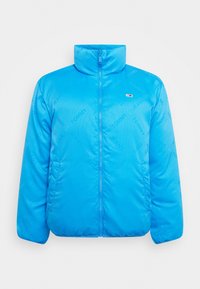 Blue puffer jacket with a high collar, front zipper, and repeat "TOMMY JEANS" branding. Made from a smooth, lightweight material.