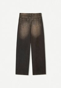 Ciemnobrązowe dżinsowe spodnie w szerokim kroju z wyraźnymi przetarciami, z dwoma tylnymi kieszeniami i prostym krojem. Dolna część nogawki jest surowa i nie wykończona.