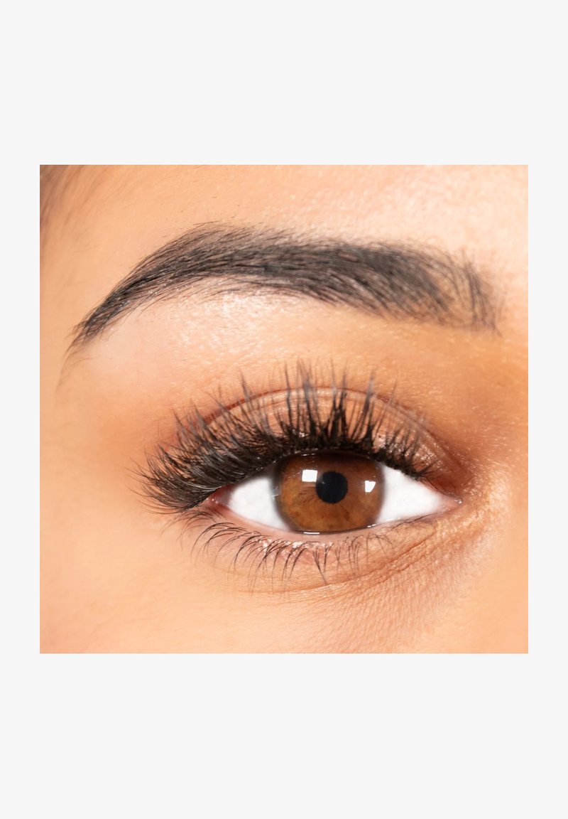 Close-up of a brown eye with long black eyelashes and a well-groomed dark eyebrow on smooth skin.