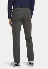 Grijze golfbroek met een gladde textuur, voorzien van een gestreepte zwart riem en een slim fit ontwerp, gecombineerd met wit en zwarte golfschoenen.