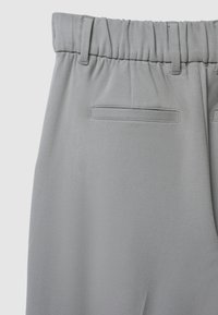 Pantaloni grigi con trama, dotati di una vita elasticizzata, presentano due tasche posteriori e passanti per la cintura. Design semplice e sartoriale senza chiusure visibili.