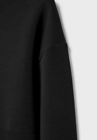 Schwarzer Sweatshirt-Stoff mit glatter Textur; gezeigt ist ein Abschnitt des Ärmels mit einem angesetzten Schulterschnitt.