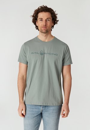 Grijze katoenen T-shirt met een ronde hals, voorzien van een donkerblauw "Sail Racing" logo op de borst, gecombineerd met lichtblauwe jeans.