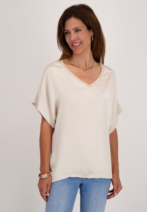 Crèmekleurige zijden blouse met een V-hals, korte mouwen en een subtiele gouden accent langs de halslijn. Zachte, gladde textuur.