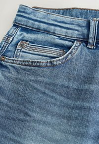 Jeansy dżinsowe w wyblakłym niebieskim kolorze o teksturowanej powierzchni, z szerokim stanem z szlufkami na pasek i małą przednią kieszonką z ozdobnym przeszyciem.