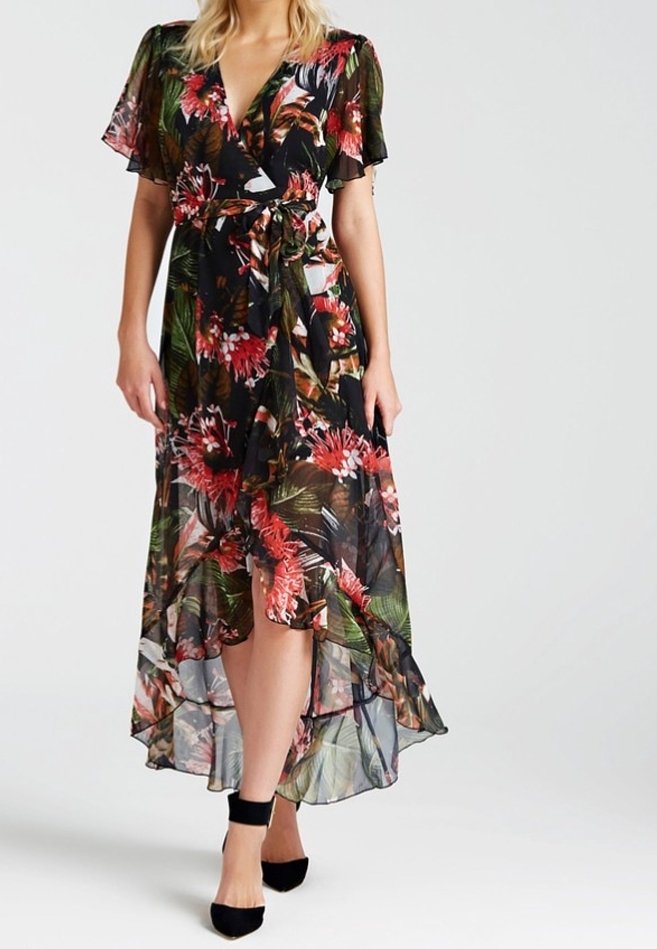 Robe portefeuille florale avec de courtes manches à volants, sur fond noir, mettant en valeur des motifs rouges et verts vibrants. Elle a un ourlet asymétrique et une ceinture à la taille.