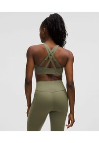 Olivengrüßer Sport-BH mit Kreuzträger-Design; aus dehnbarem Material. Hochgeschnittene passende Leggings mit Nahtdetails und Taschen.