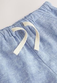 Modri kratki hlači iz blaga z zateznim trakom v pasu in bež vrvicami, mehke teksture z rahlo meliranim vzorcem.