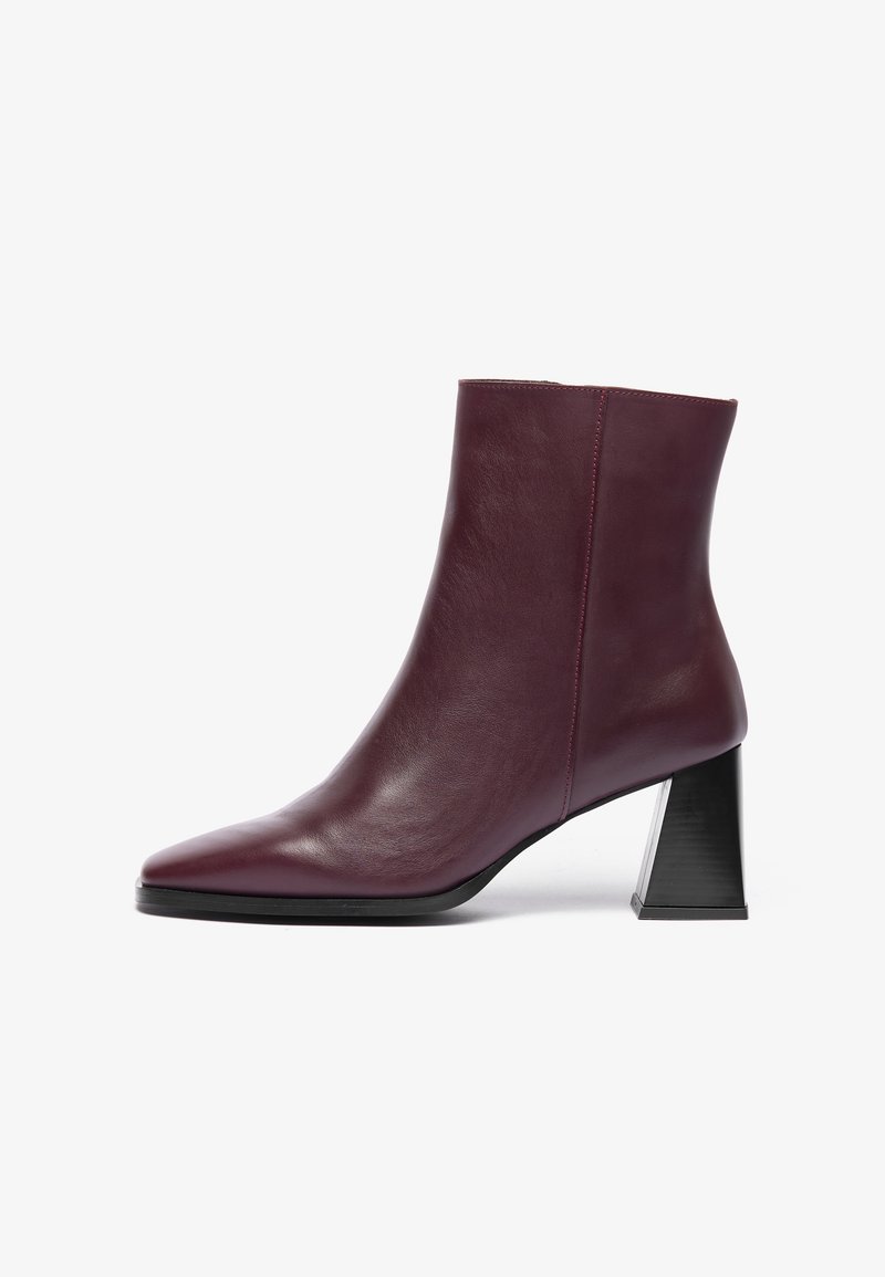Bottine en cuir bordeaux à bout pointu et à talon géométrique noir épais ; texture lisse avec des détails de couture minimaux.