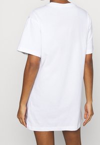 T-shirt bianca in cotone, vestibilità comoda, maniche corte, scollatura rotonda, design semplice, senza motivo o grafiche visibili, con orlo dritto.