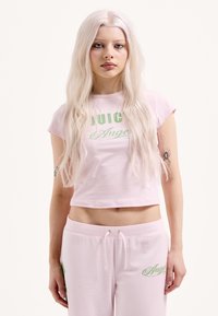 Rózsaszín rövid felső, melyen zöld színnel a "JUICE" és az "Angel" felirat látható. Párosítva ugyanilyen rózsaszín szabadidőnadrággal, amely zöld hímzéssel díszített.