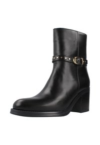 Botín negro de cuero hasta el tobillo con punta redondeada, tacón ancho y una correa con tachuelas circulares y detalle de hebilla. Textura suave.