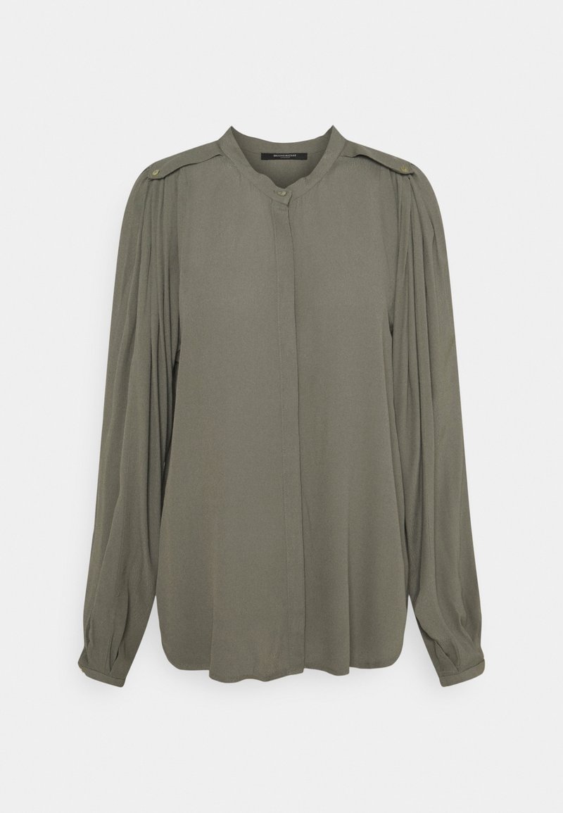 Långärmad blus i olivgrön med plisserade axlar, dold knappslå och knäppte ärmslut på en enfärgad bakgrund.