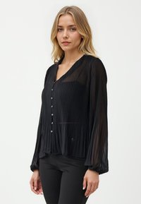 Schwarze plissierte Bluse mit langen Ärmeln, V-Ausschnitt, Knopfleiste und subtilem Glanz. Sie hat elastische Bündchen und eine lockere Passform.
