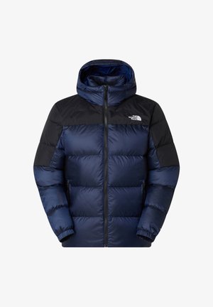 Námorně modrá prošívaná bunda s černým ramenním oděvem, předním zipem a kapucí. Materiál je hladký s prošívanými sekcemi. Logo na hrudi.