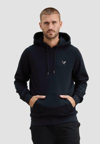 Felpa nera con cappuccio e tasca frontale, cappuccio regolabile con coulisse e polsini a coste. Presenta un piccolo logo con spade incrociate sul petto.