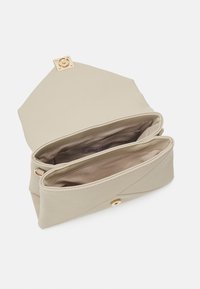 Beige clutch-taske lavet af blødt materiale, med en guld metal snap-lukning og to indvendige rum til organisering.