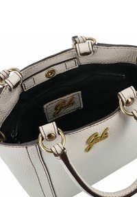 Sac à main en cuir texturé blanc avec des accents marron, quincaillerie dorée et une poche intérieure zippée. Présente un logo et des poignées robustes.