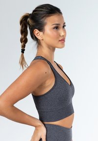 Sujetador deportivo de canalé gris oscuro con un escote en V profundo, tirantes anchos y un dobladillo elástico. Textura suave y diseño ceñido al cuerpo.